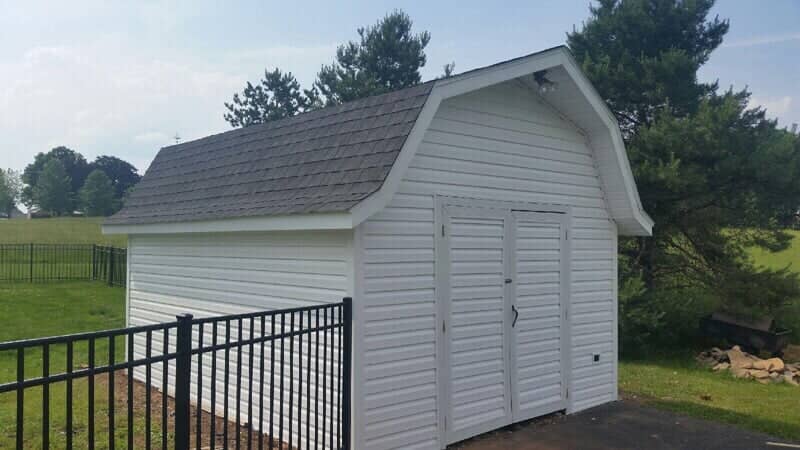 White outbuilding with a new gambrel-style shingle roof