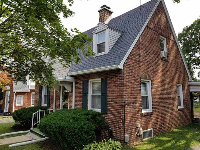 Brick Cape Cod home with a new dark grey shingle roof