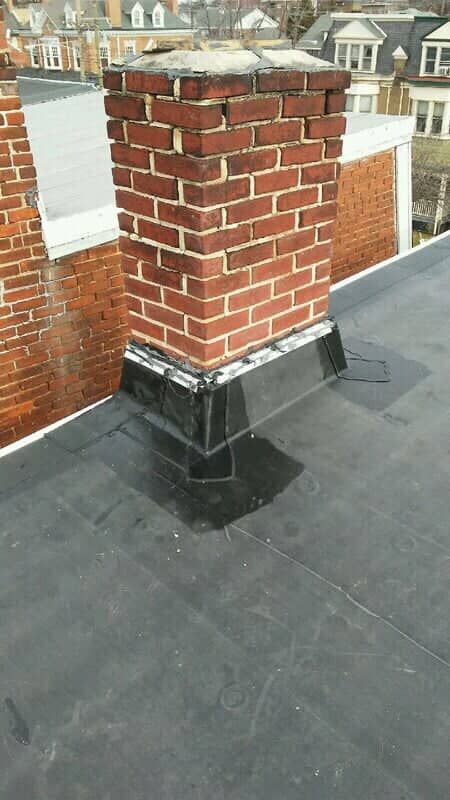 Brick chimney with new flashing and a flat rubber roof
