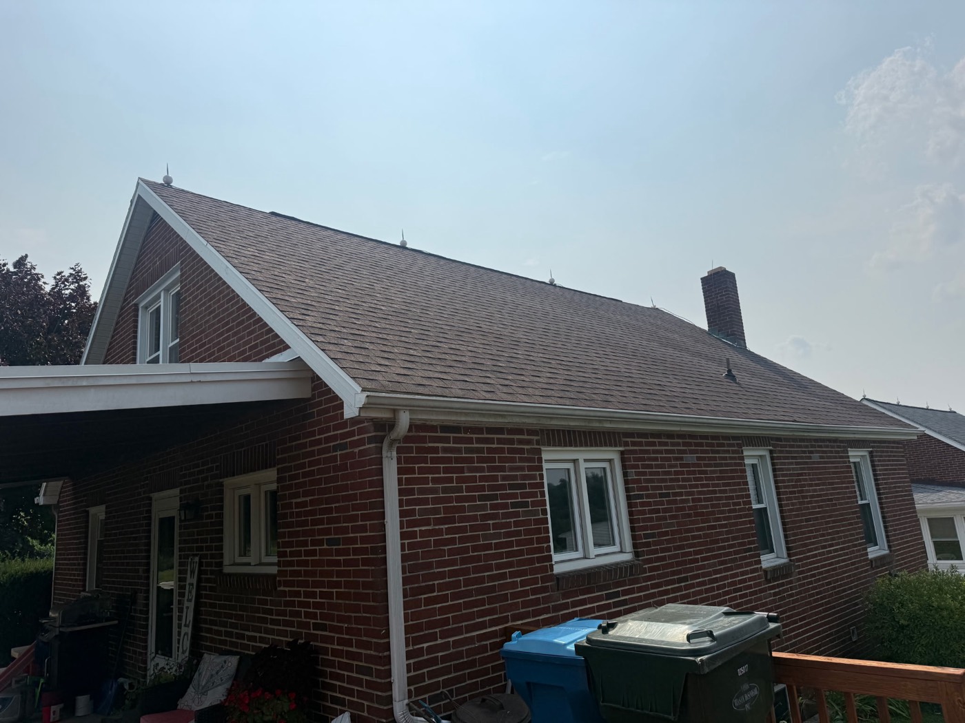 Brick Cape Cod home with a new brown architectural shingle roof and an attached carport