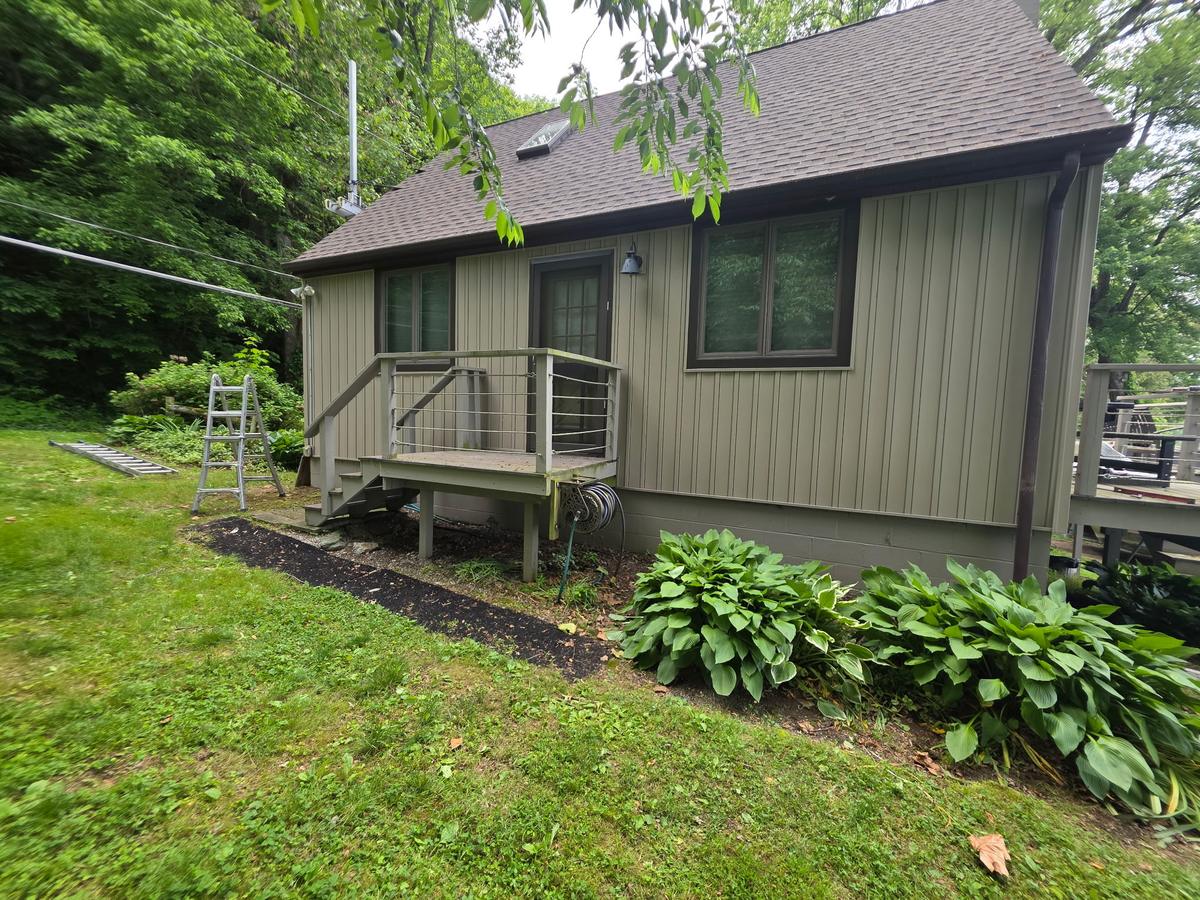 Rear of a lake cabin with a new dark shingle roof and deck