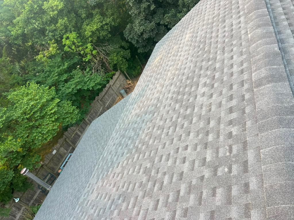 New grey architectural shingle roof on a home backing up to a wooded lot and privacy fence