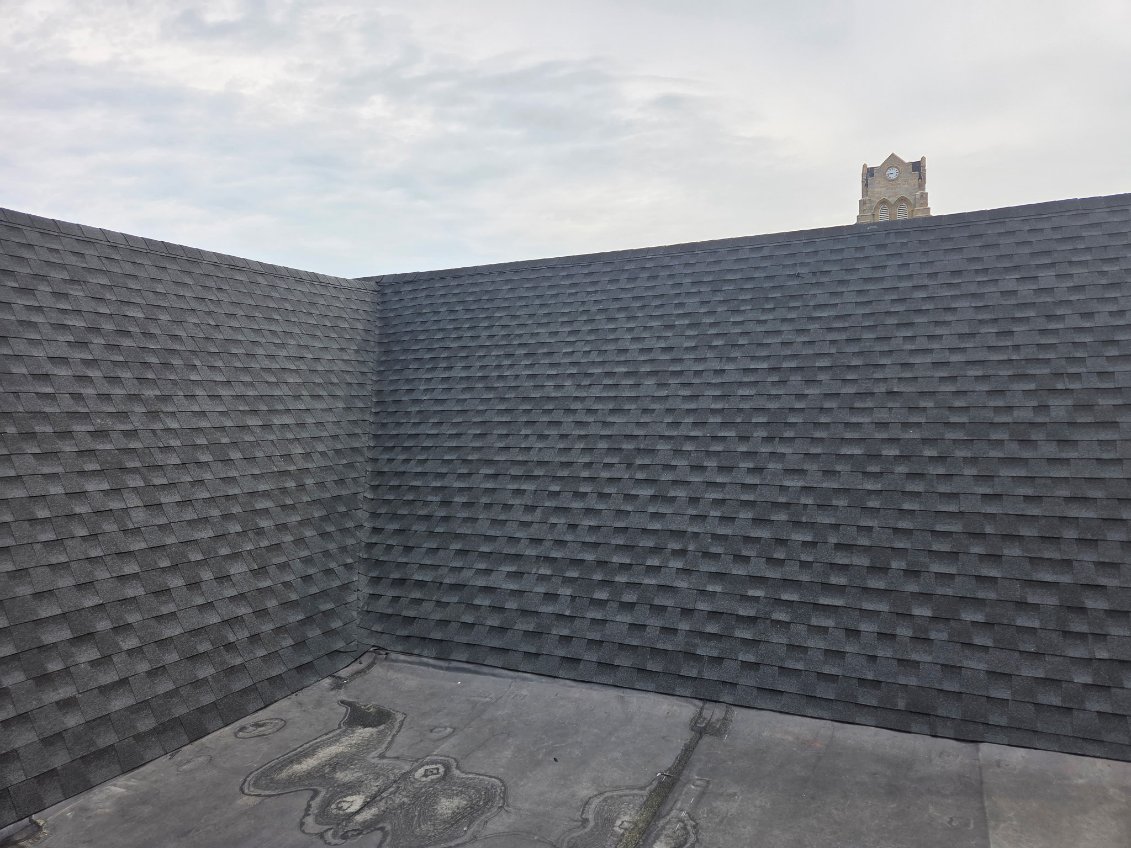 New grey architectural shingle mansard roof on a downtown building near a clock tower