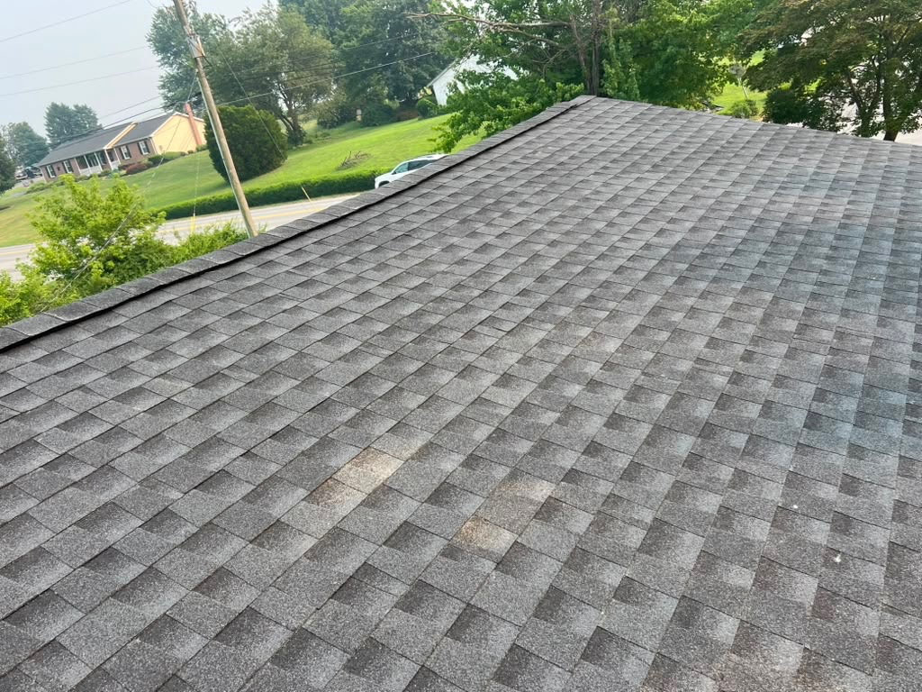 New weathered-grey architectural shingle roof seen along the ridge with a neighborhood street beyond